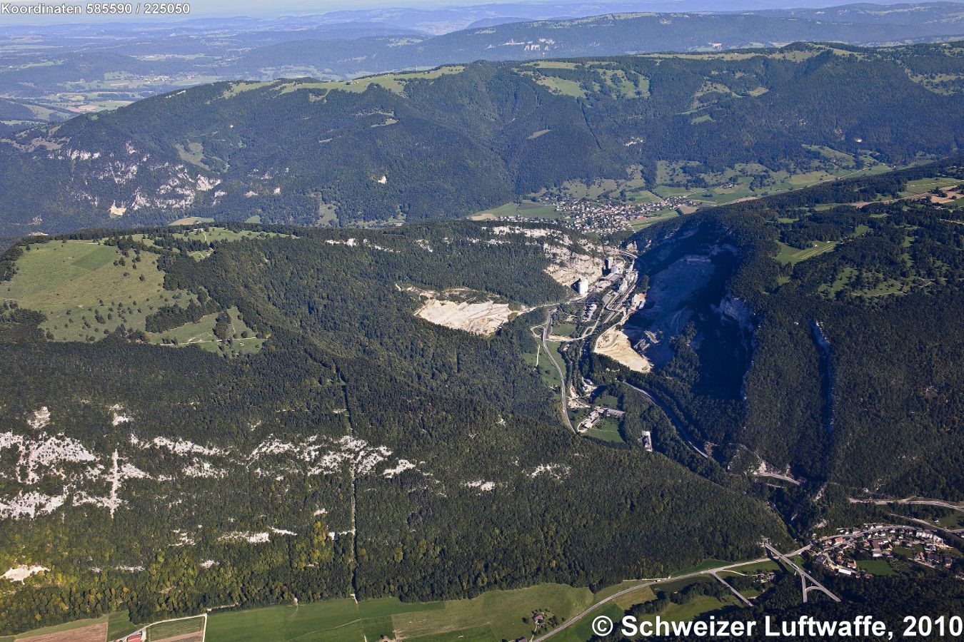 Klus von Reuchenette (Position: 2'585'604.84, 1'225'980.76, Norden: oben). Unten am Bildrand rechts: Brücke der Transjurane mit dem Ort Frinvillier. Zementwerk in der Klus. Dahinter im Tal des Terbez die Ortschaft Péry. Klus durch den nächsten Hügelzug (oben im Bild): Sonceboz; Vallée de Tavannes.
